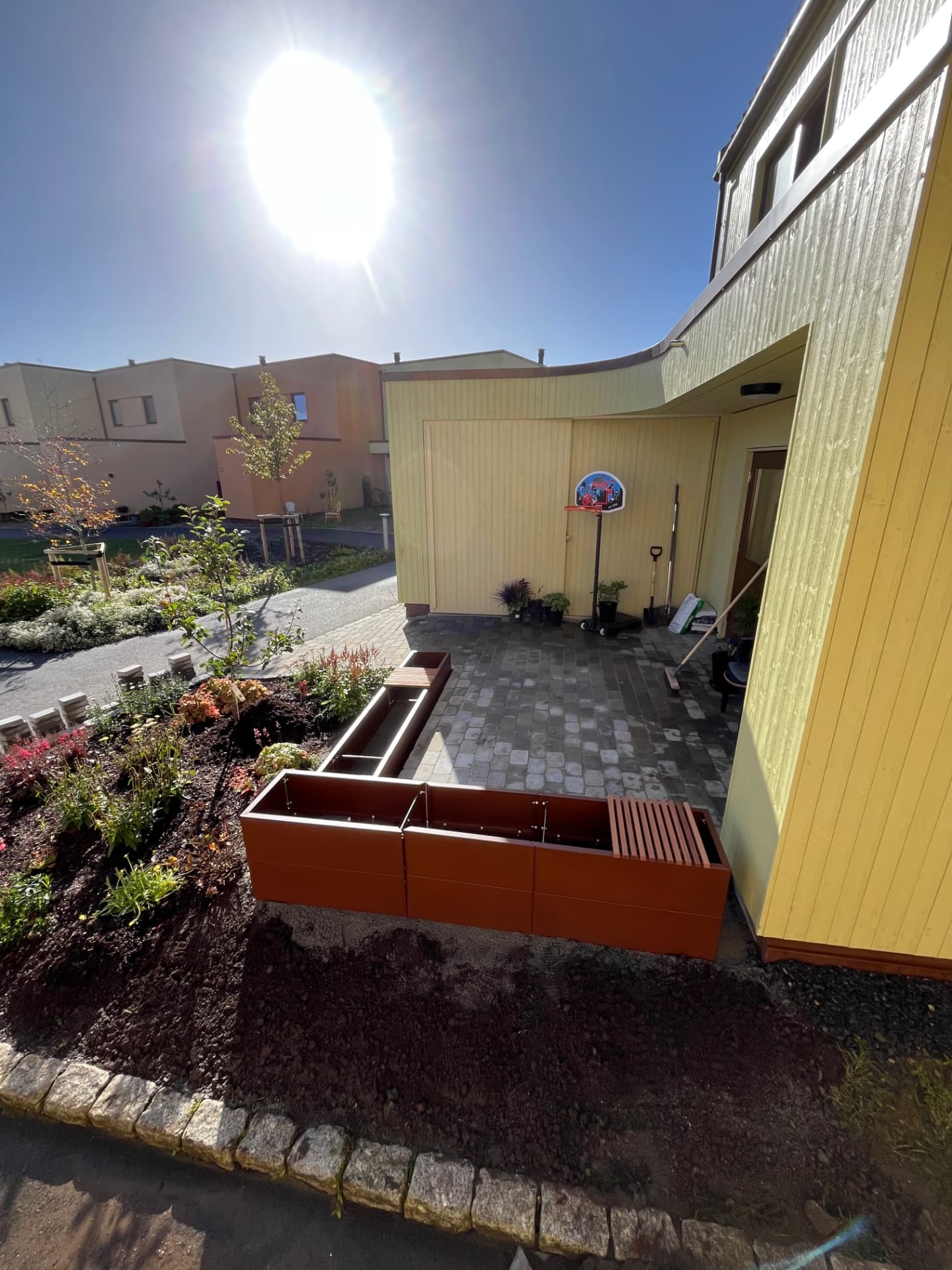 Ferdig tilpassede blomsterkasser ved belegningssteinen og husveggen