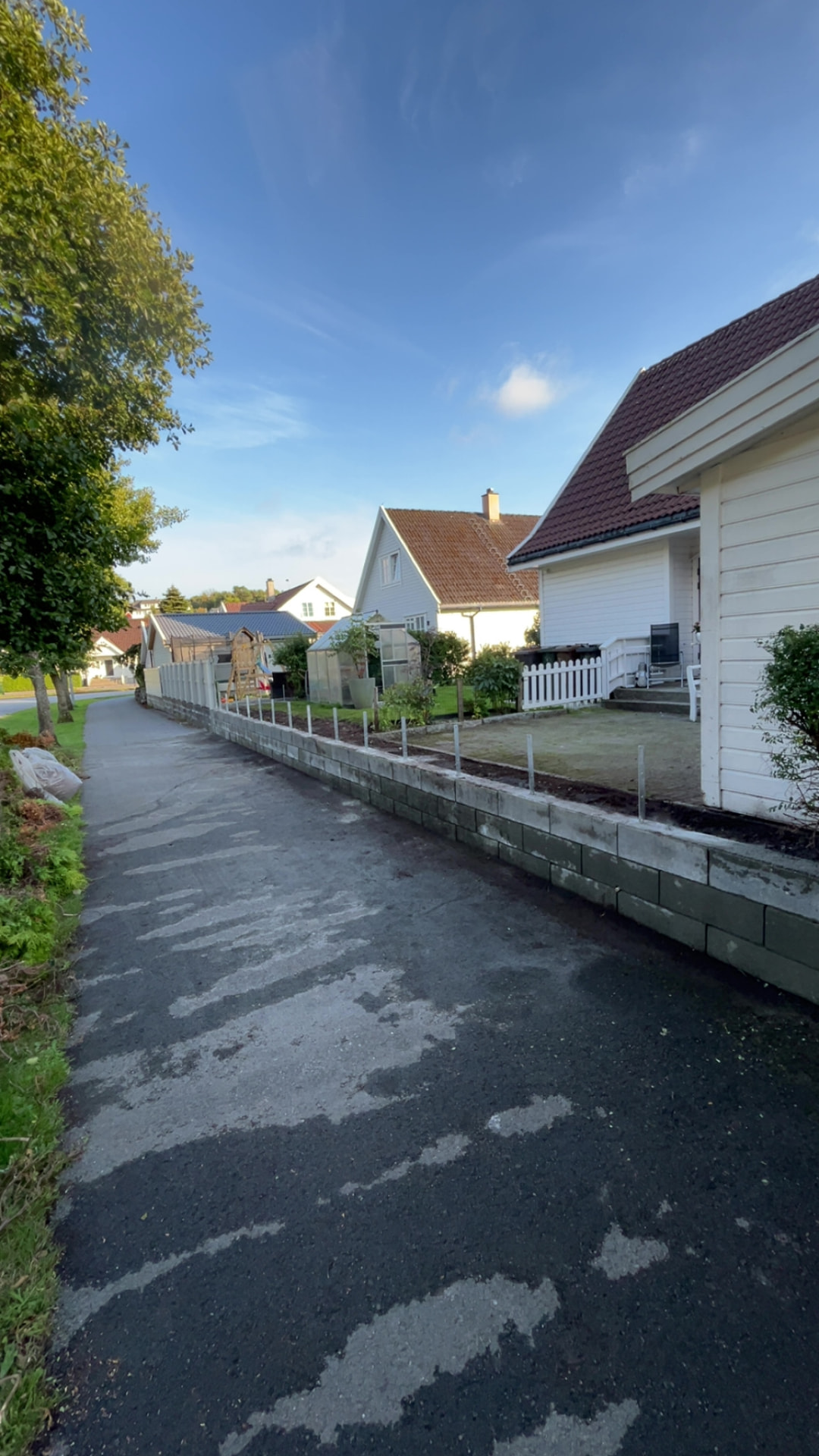 Betongmuren med monterte stolpestøtter sett fra veien
