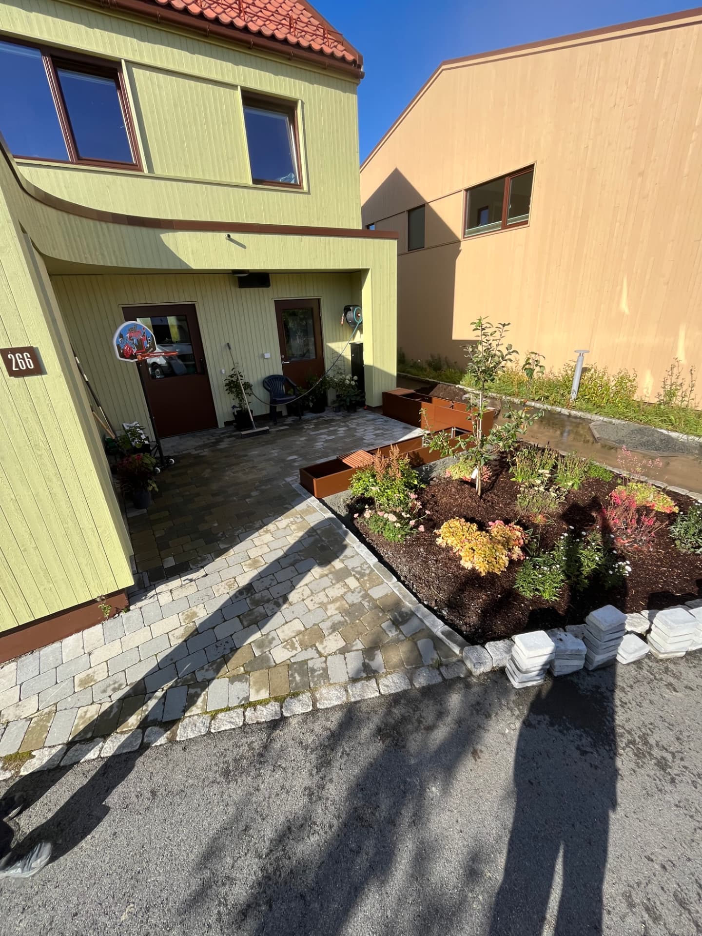 Inngangspartiet med ferdig belegningsstein, blomsterkasser og planert underlag