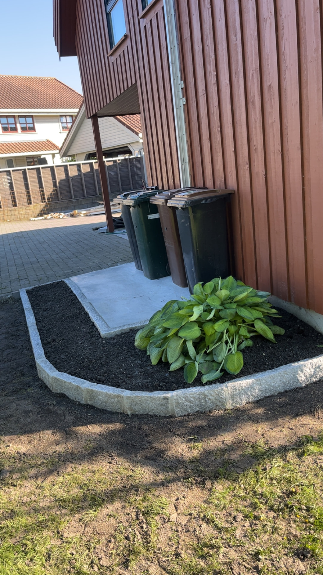 Ferdig bed med kantstein i granitt og planter inntil husveggen