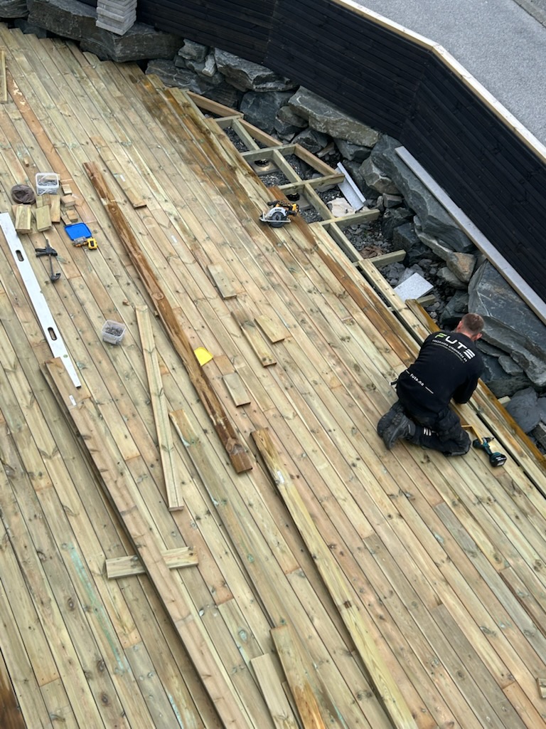 Legging og tilpasning av terrassebord med verktøy på arbeidsflaten