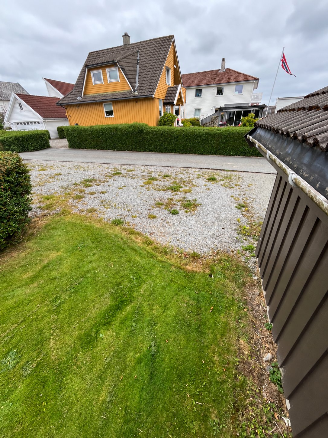 Hagen med plen og grusflate mot veien før opparbeidelsen