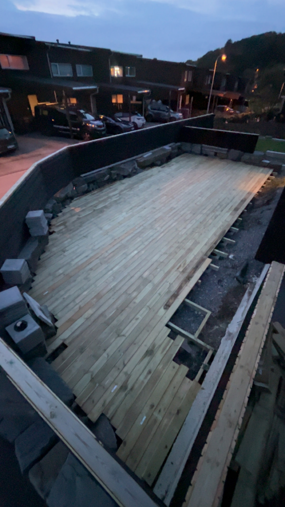 Terrasse under bygging i skumringen med åpne felt langs kanten