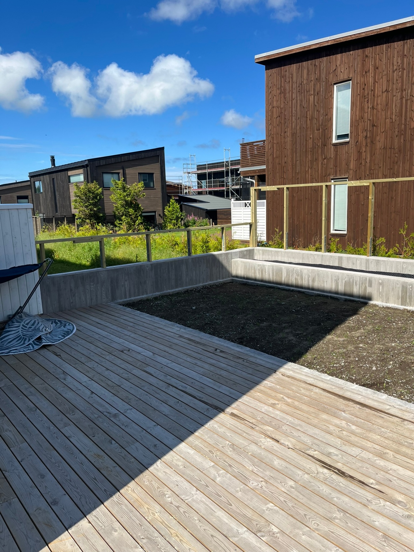 Uteplass klargjort for plen — terrasse på plass og jord planert mellom støttemurer