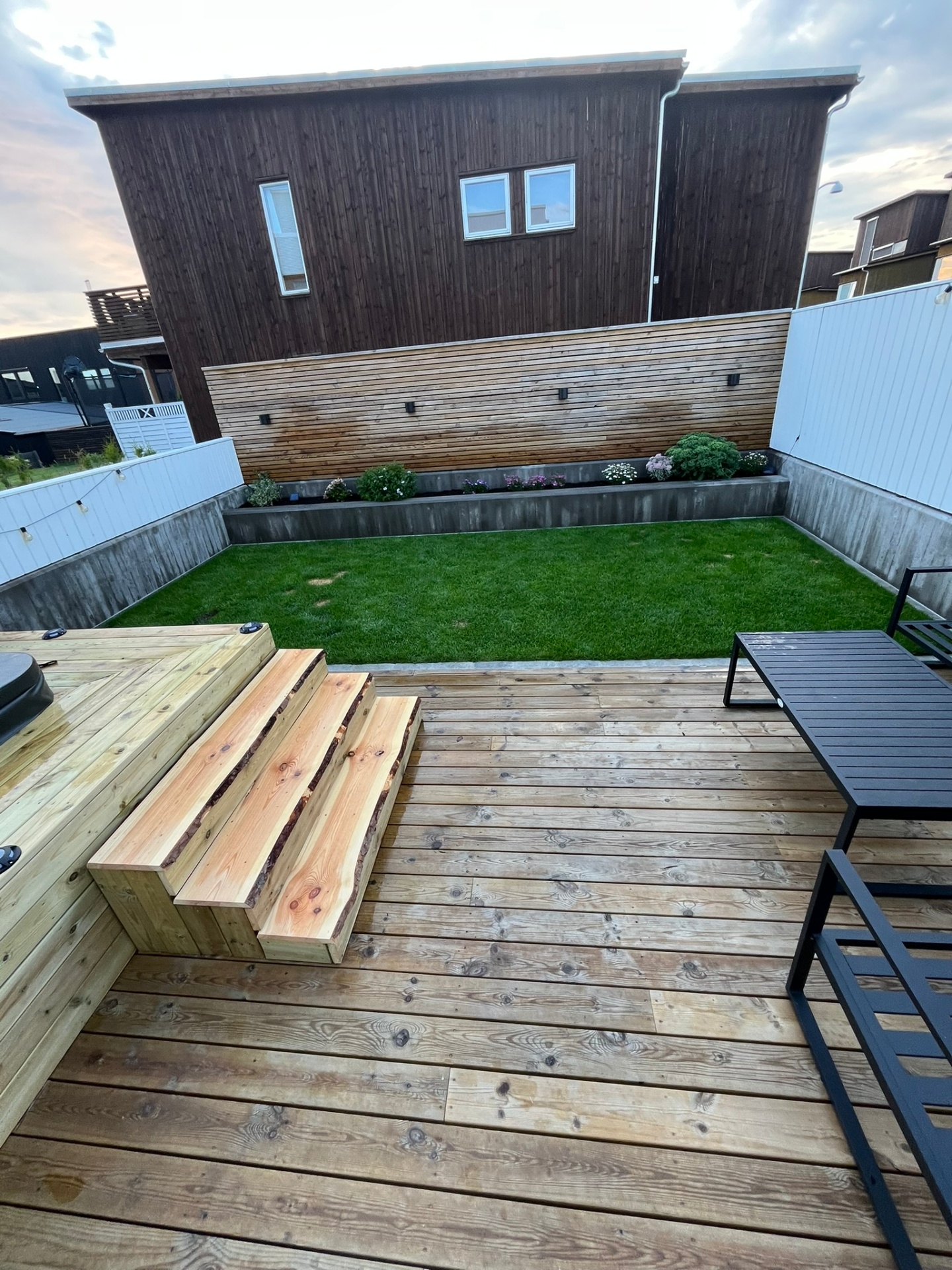 Ferdig uteplass med plen, terrasse, plantefelt og horisontal spilevegg i rekkehusprosjekt