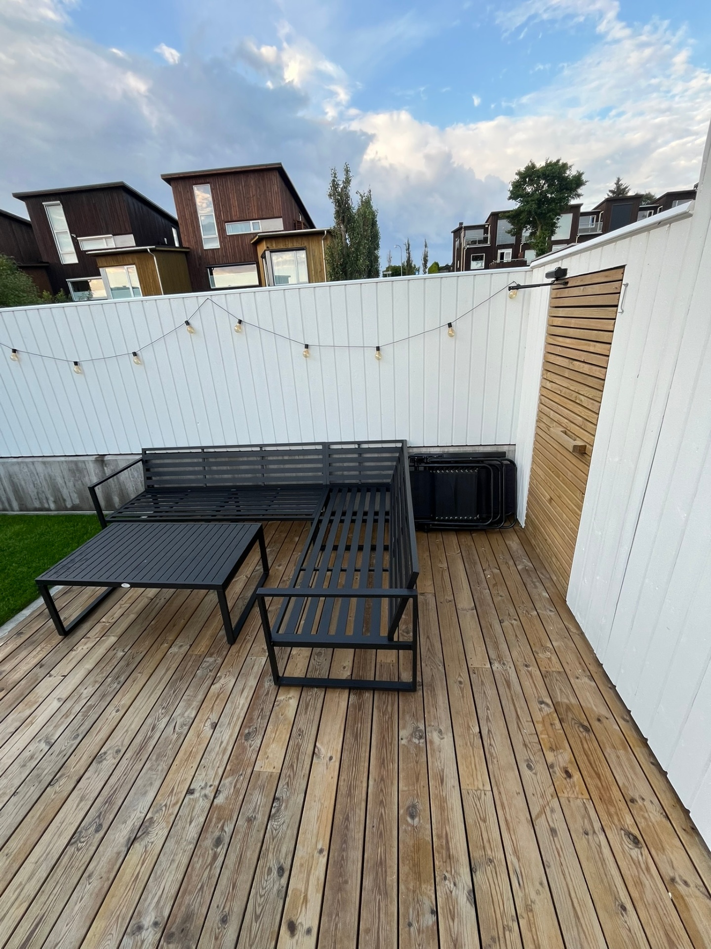 Ferdig terrasse med svart loungemøblement og lyslenke